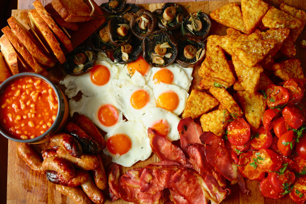 A large full english breakfast served on a wood board